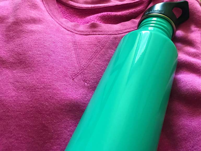 A pink sweather and blue water bottle.