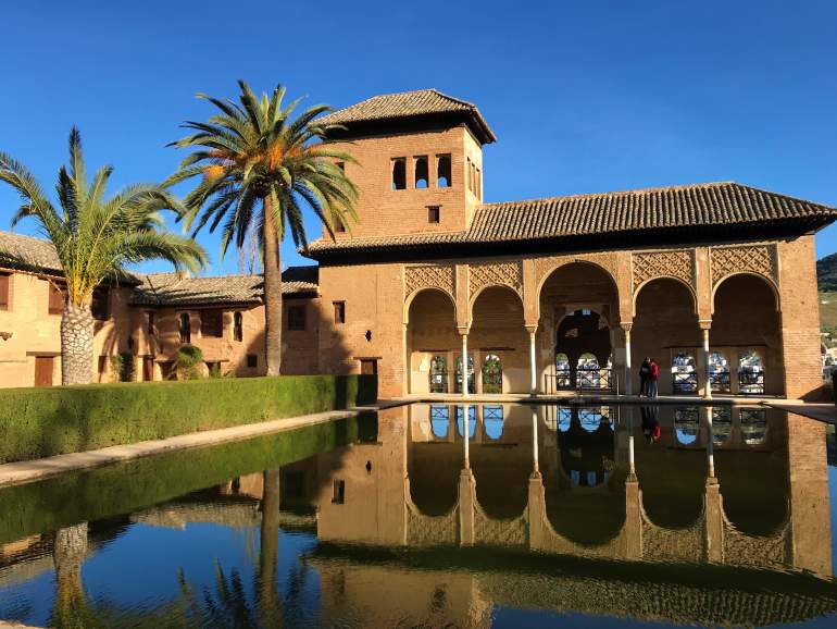 A portion of the Nasrid Palaces with a reflection on a pond.